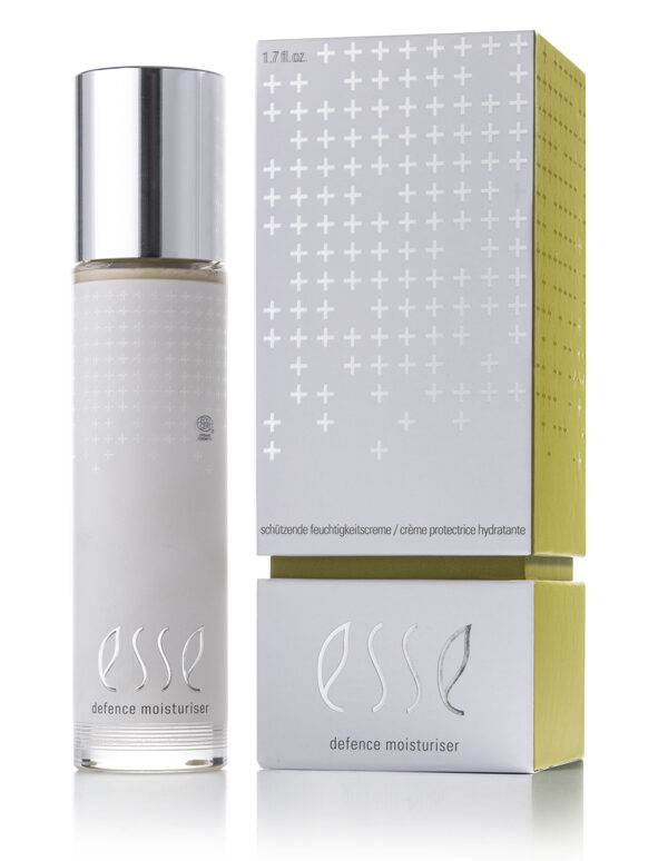 A bottle of Esse Defence Moisturiser with a silver cap stands beside its matching silver and yellow box, both showing modern white plus signs and Esse Defence Moisturiser branding.