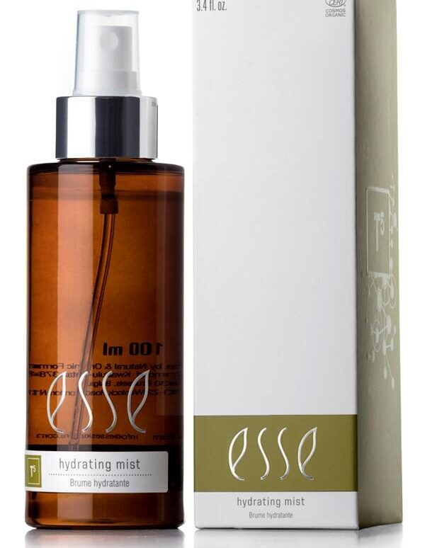 An Esse Hydrating Mist bottle in brown with a white pump is placed beside its matching white and green box. The bottle is labeled "100 ml" and "Hydrating Mist," while the box features consistent branding with "3.4 fl. oz." text.