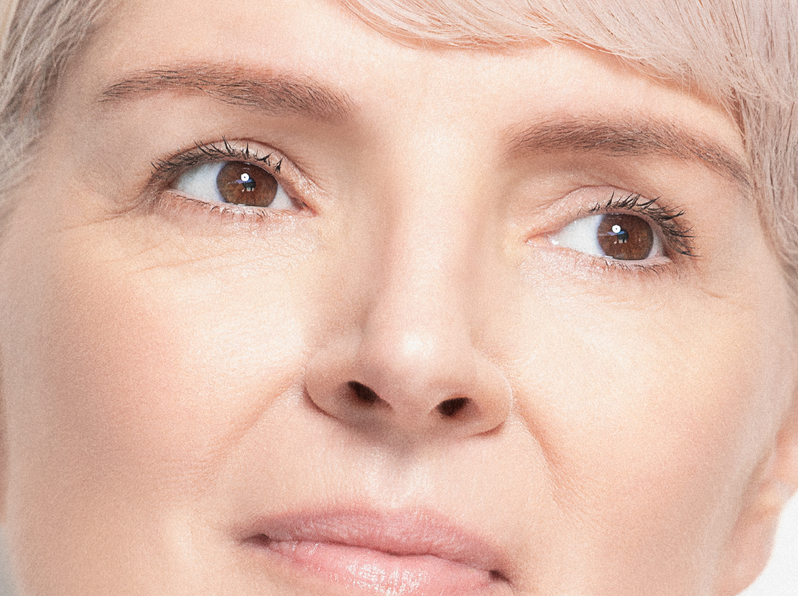 Close-up of a woman's face showing her eyes, nose, and part of her mouth. She has light skin, light hair, and is looking slightly to the right with a calm expression.