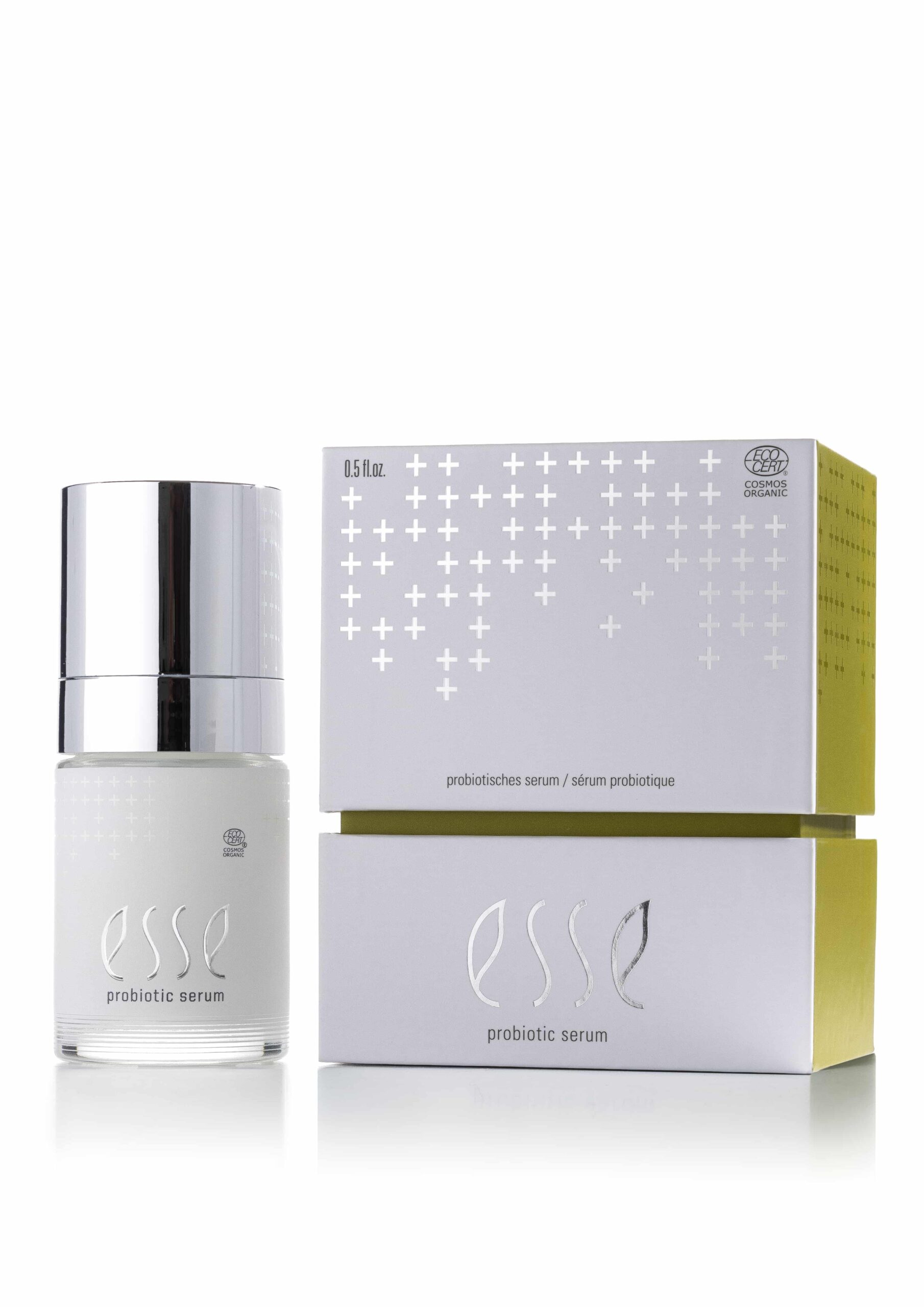 An Esse Probiotic Serum bottle with a silver cap is shown beside its white packaging box, which has silver and yellow accents and a plus sign pattern.
